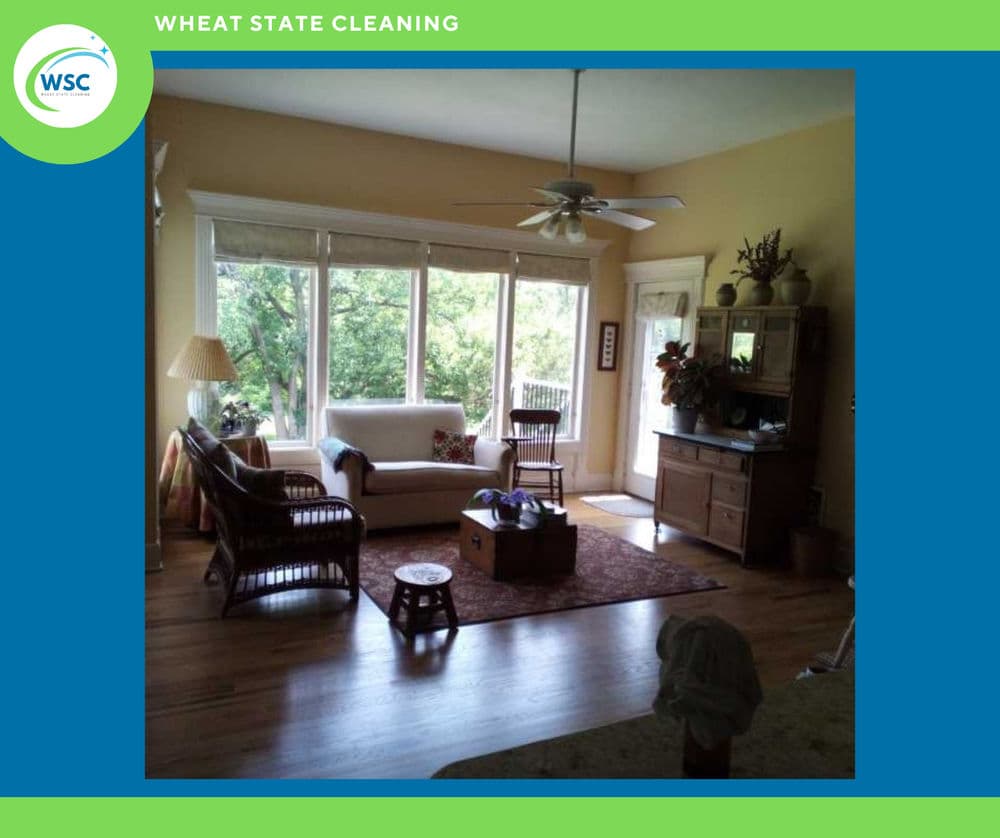 Bright living room with large windows, comfortable seating, and wooden furniture.